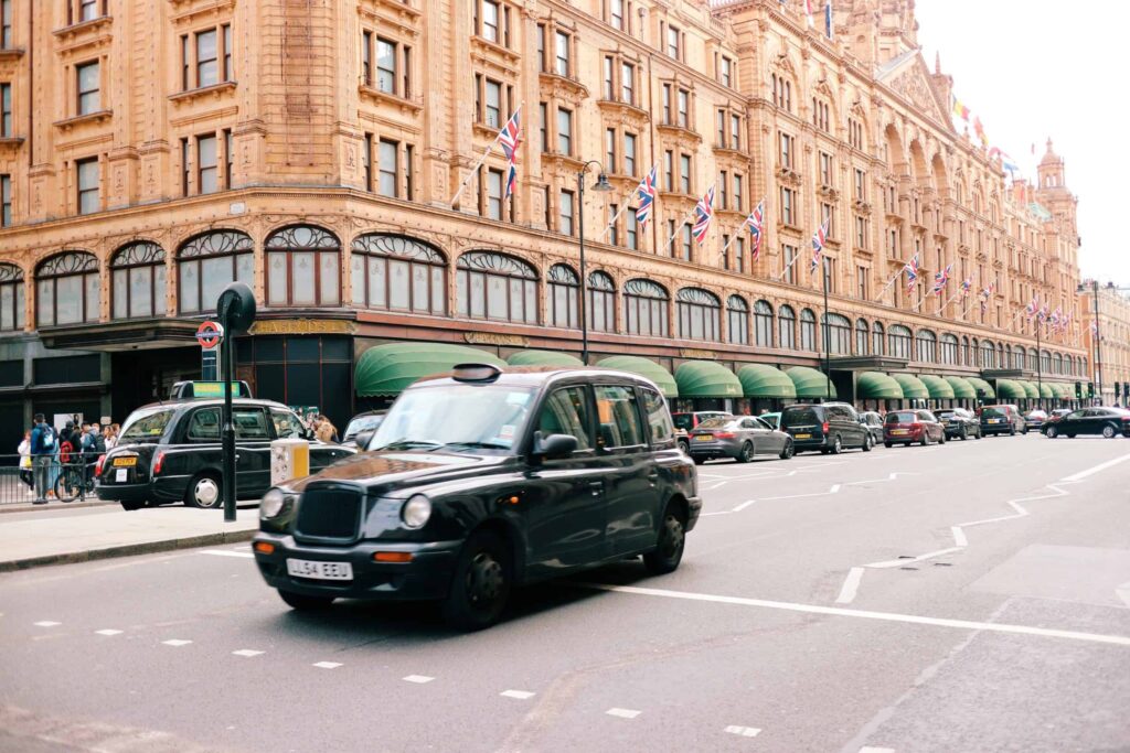 A photo of a Northwest London street with a black cab in front of Harrods